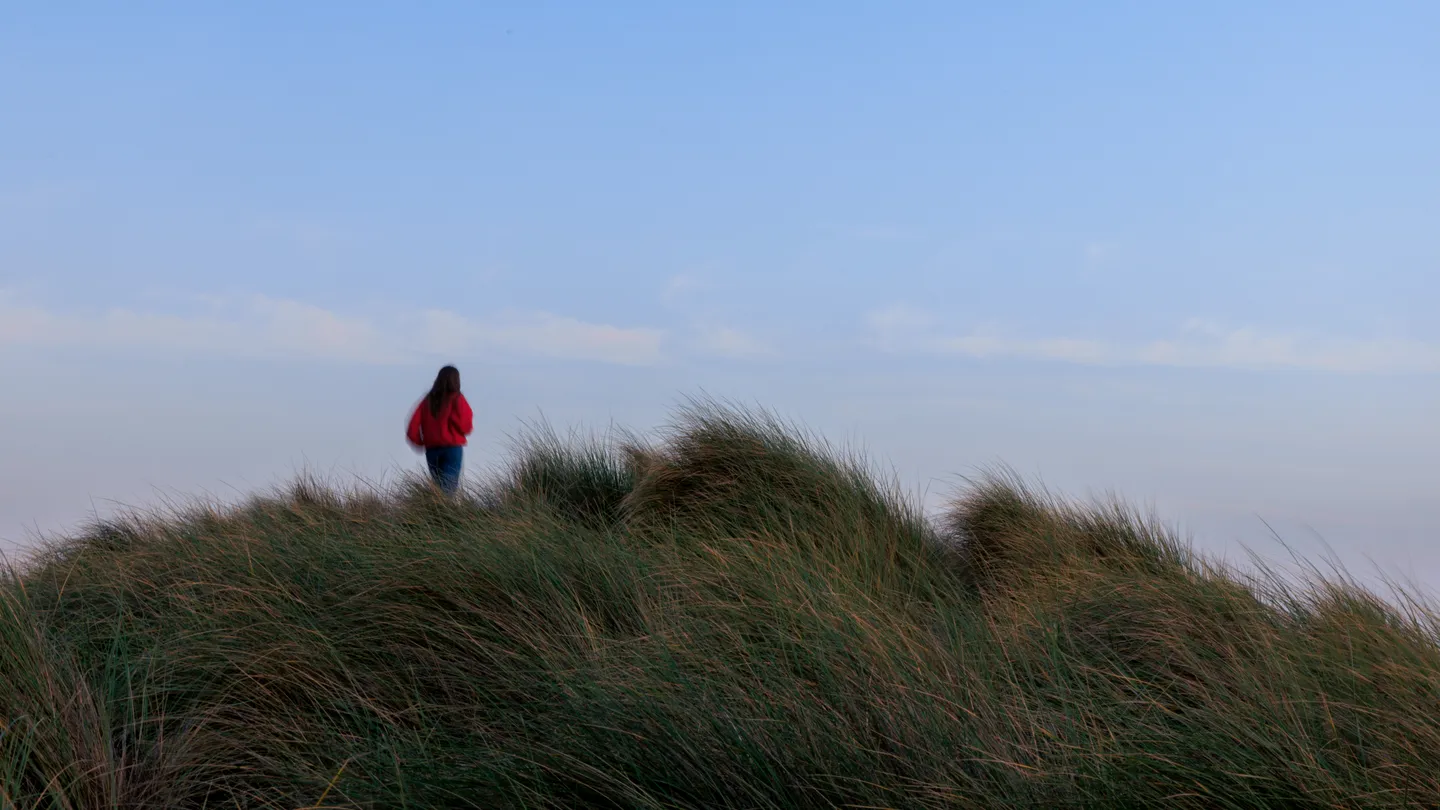 Aleli standing among beach dunes beneath a blue sky