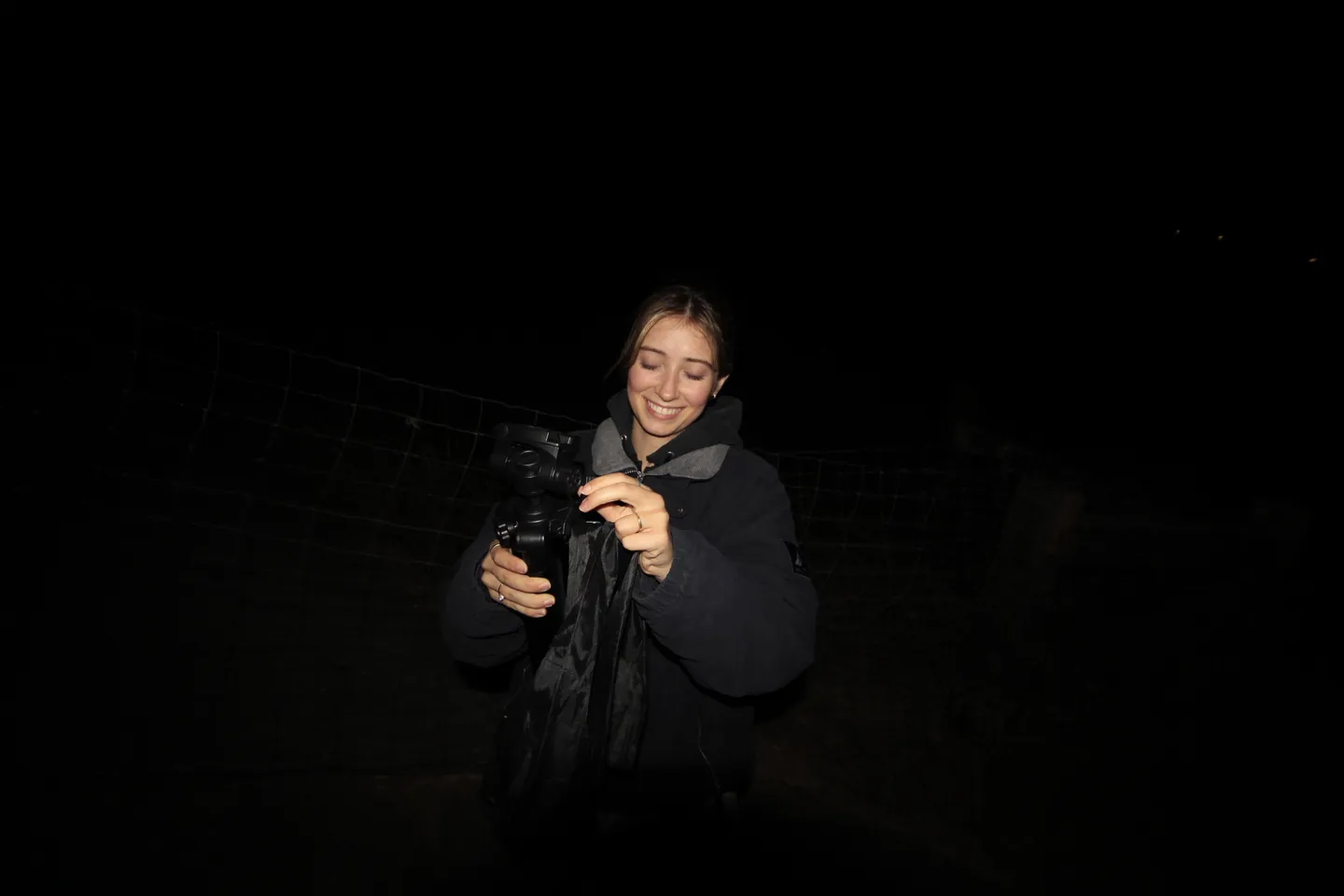 Aleli holding her camera against a dark background