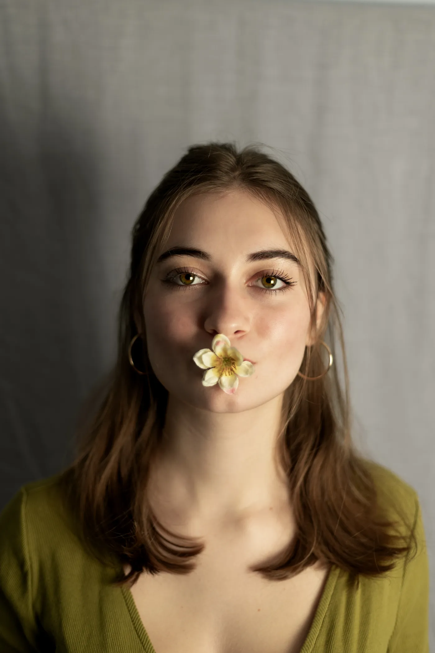 Headshot of a woman holding a flower in her mouth