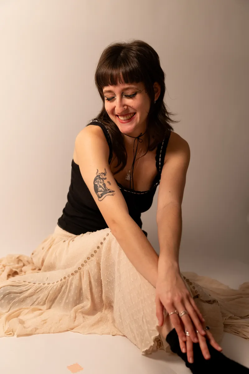 Seated portrait smiling down at a tattoo