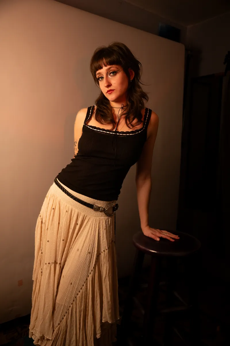 Full-length portrait leaning on a stool in warm light