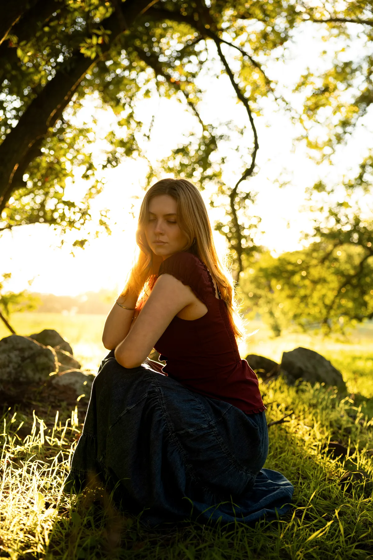 Julia kneeling in grass beneath an oak tree